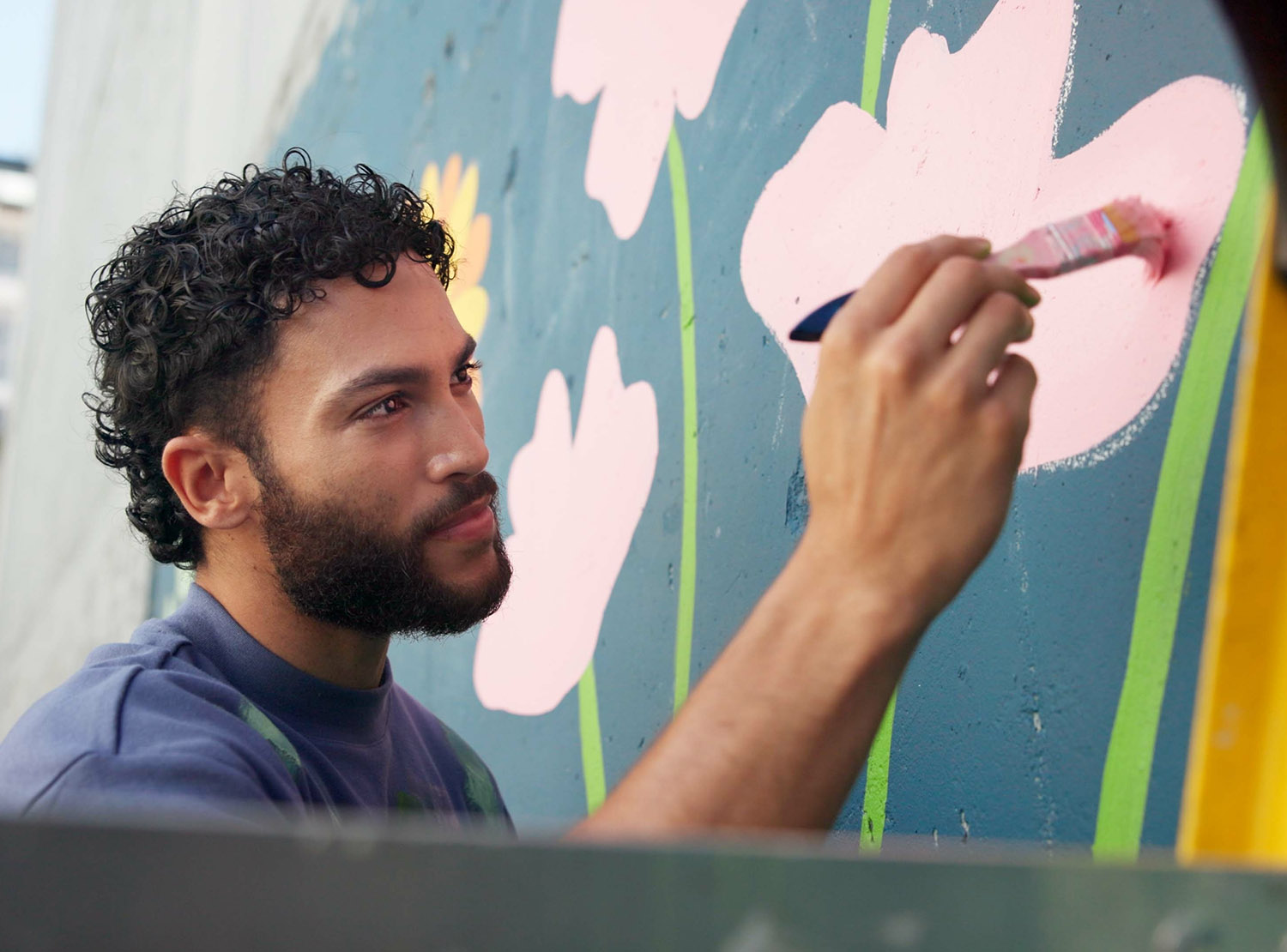 Man painting a mural on side of building. 