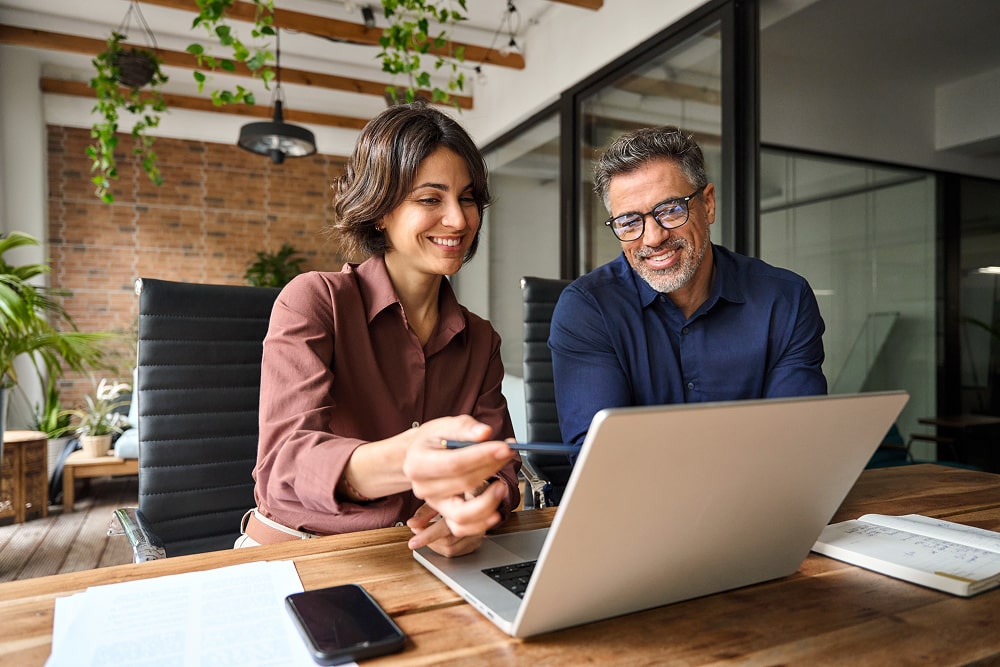 Two professionals sitting by laptop.