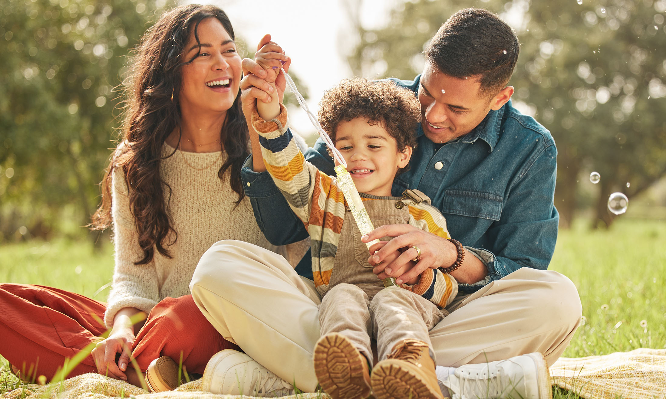 Two parents and son sitting in a park. 