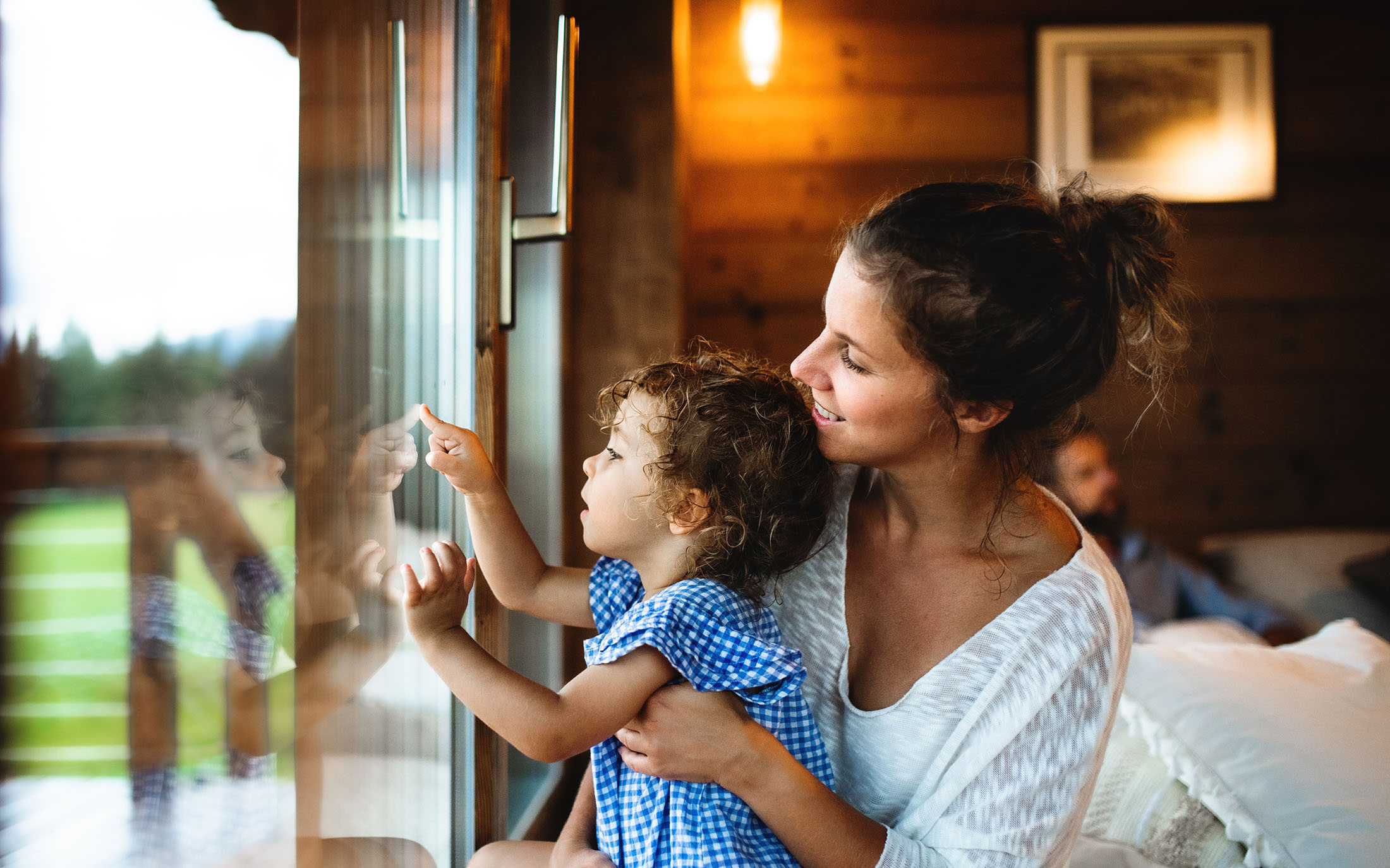 Woman holding baby by window. 