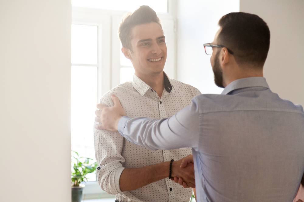 Two people standing shaking hands. 