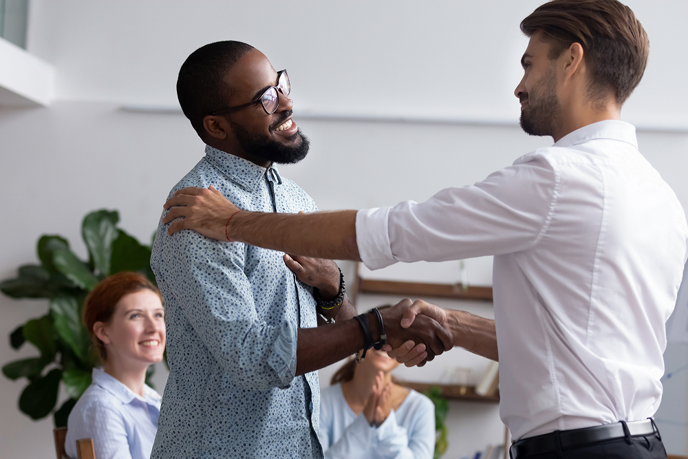 Two men standing shaking hands. 