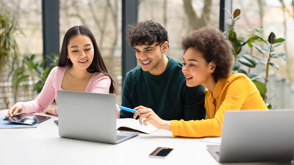 Three students sitting at a laptop.