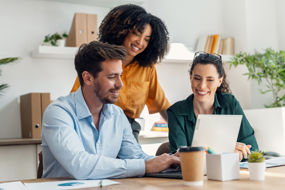 Three people standing around laptop